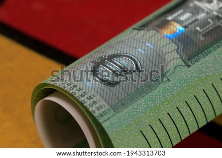 The Euro banknote has been rolled into a roll and shows the symbol of the euro. Euro banknotes are not made of paper, but of pure cotton fiber to improve their durability.