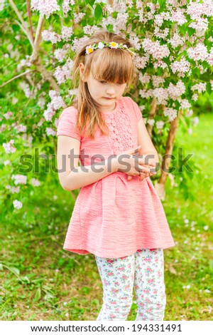 Outdoor portrait of a cute little girl on a nice sunny day, wearing coral dress and printed leggings