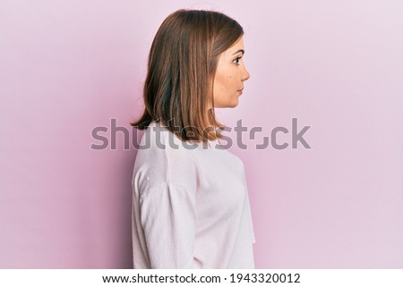 Young beautiful woman wearing casual clothes looking to side, relax profile pose with natural face with confident smile. 