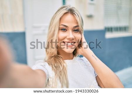 Young caucasian girl smiling happy making selfie by the camera at street of city.