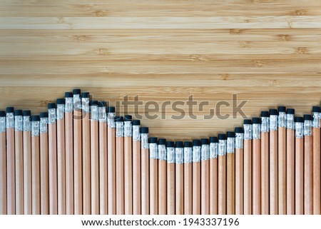 Top view of several pencils located in row on wooden table. Sharp pens laying in chaotic order. Tool for drawings on paper. Equipment for art concept