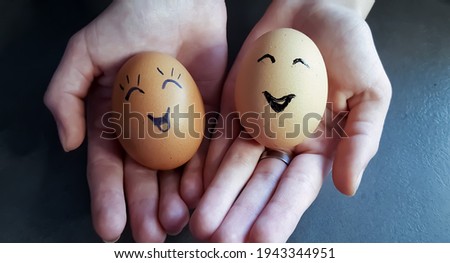 Two Easter eggs decorated in the form of cheerful face in his hands