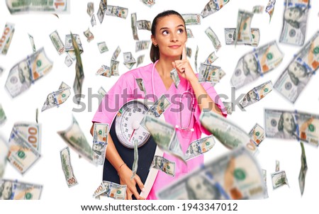 Young hispanic woman as nutritionist doctor holding weighing machine serious face thinking about question with hand on chin, thoughtful about confusing idea