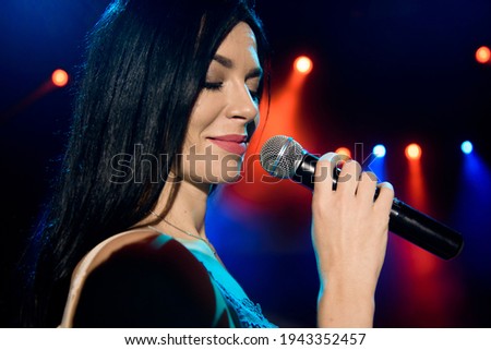 Singer with microphone on the colorful light stage background