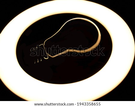 Lamp night light in a dark background. Vintage effect style picture. ring lamp. Incandescent lamp inside LED ring light source Concept photography, the light takes the form of an incandescent lamp