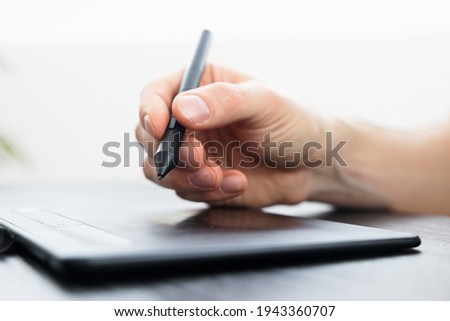 Image processing using a graphics tablet. Male artist works with the pen of a graphic tablet.