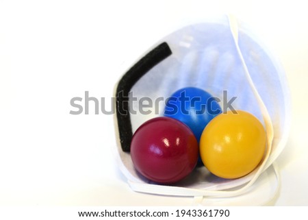 Colorful Easter eggs lie in a FFP2 mask in front of a white background