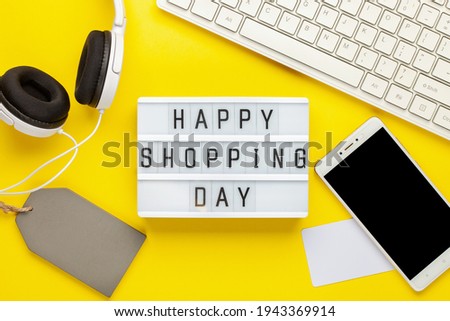 Happy Shopping Day  text on lightbox on a yellow paper background . Design for promotion of winter end of year sale. Flat lay. Top view
