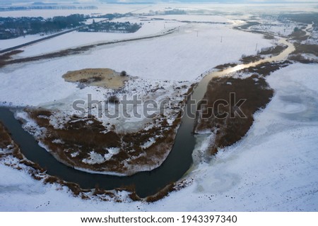 Beautiful snow-covered landscape of the winding river floodplain in winter. Amazing textures of nature. Eastern Europe. Aerial photography