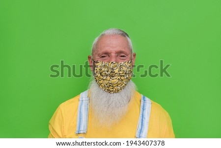 Trendy hipster senior man looking in camera while wearing safety face mask for coronvirus outbreak