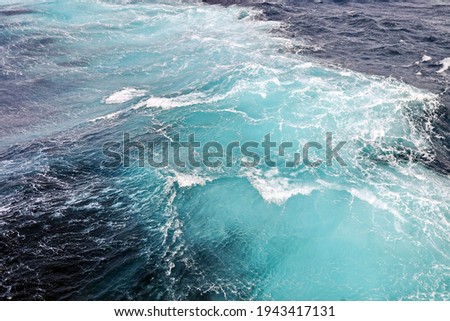 Storm waves in the world ocean. Kind of waves, crests, splashes, foam against the background of the sea and blue sky.