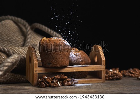 Cupcakes sprinkled with powdered sugar on a dark background. Confectionery on a black background. Walnut muffins