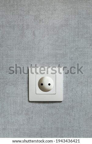 Electrical outlet on the gray wall. Electricity, safety, energy saving concept. Vertical. Copy space