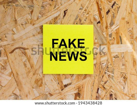 Yellow Sticker with text Fake News on the wooden background. Concept photo