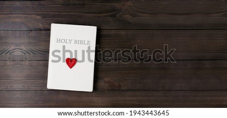 The closed book is the Holy Bible. Scripture. Heart. Love. Prayer. On a wooden table.