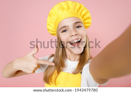 Close up teen girl chef cook confectioner housewife baker in yellow apron white t-shirt cap do selfie shot on mobile phone point finger on herself isolated on pink background studio. Food cake concept