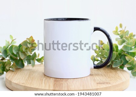 Blank black handle mug mockup photo with eucalyptus ,black rim mug on wood table Royalty-Free Stock Photo #1943481007