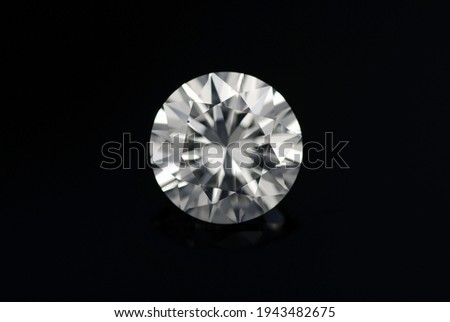 Round diamond faceted cubic zirconia, cubic crystalline form of zirconium dioxide (ZrO2) colorless synthesized material. White synthetic gemstone. Diamond imitation. Black isolated background. Royalty-Free Stock Photo #1943482675