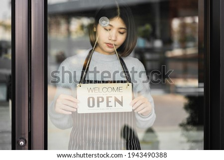 young woman owner coffee shop turning signboard to open a coffee shop, after due to the pandemic of coronavirus or COVID-19