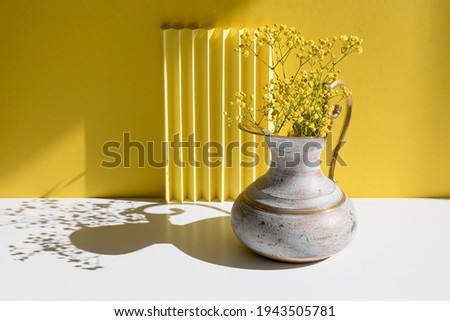 A bouquet of Gypsophila in a brass jug with harsh shadow. Minimal interior decoration concept. Minimal summer concept. Copy space. 
