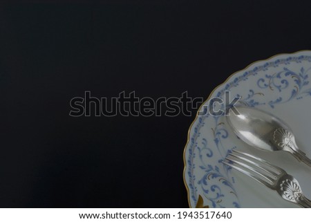 Lay out of vintage old silver cutlery. made in England. 
spoon, fork and picture plate on black background.  

Top view photo ・soft focus image. 