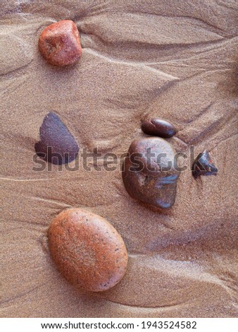 Pebbles in the sand at Legzira beach at the shore of the Atlantic Ocean, north of the town of Sidi Ifni, Southwest Morocco