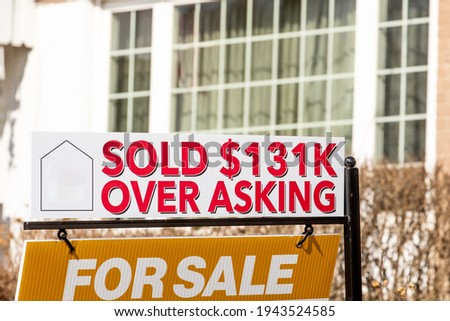 A real estate For Sales sign with  a Sold $131K Over Asking notice suggesting a hot or overheated housing market