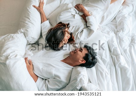 Asian couples is laying on bed in the bed room at modern home.Couple in Valentine day.Love couple,Relationship and couple concept. Royalty-Free Stock Photo #1943535121