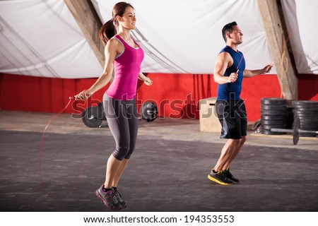 Young man and woman jumping ropes as part of their workout in a gym Royalty-Free Stock Photo #194353553