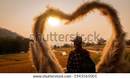 A young man sitting at the heart of the evening sunset in the barley field