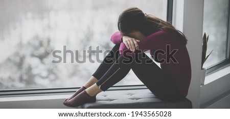 Sad crying young woman hiding face in sadness alone at home in isolation. Mental health problem social anxiety panic attack ptsd effects from the coronavirus pandemic. Royalty-Free Stock Photo #1943565028