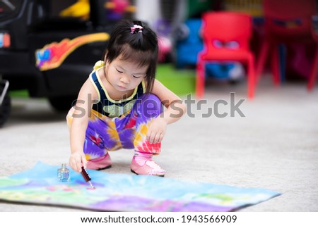 Cute girl is using a nail polish with a glitter to decorate the art on a piece of paper. Asian child intend to make crafts. Children enjoy learning. Asian  kids aged 3-4 years old. Royalty-Free Stock Photo #1943566909