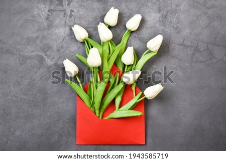 Greeting card mockup with tulips flowers bouquet and envelope on gray background.Red envelope full of tulips. Copy space,flat lay. creative composition.