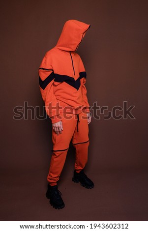 man in a closed orange tracksuit on the front