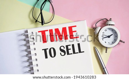 TIME TO SELL on the notebook with pen,alarm clock on pink background