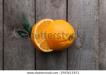 Flat lay with fresh ripe sliced halves of orange fruit on gray wooden background. Orange pulp and green leaves. Tropic food concept. Healthy eating concept. High quality photo