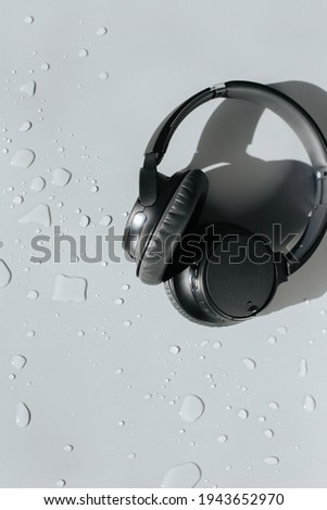 Grey background with black headphones on a water drop surface, add your own logo, story, mockup