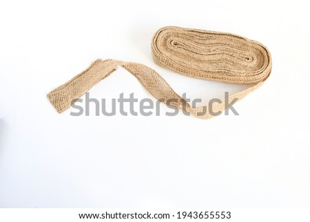 Top view roll nature burlap fabric patch label,  on white background ,Sackcloth piece idea for creative ,hobby vintage style and decorative in house.