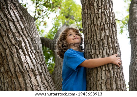 Young boy hugging a tree branch. Little boy kid on a tree branch. Child climbs a tree Royalty-Free Stock Photo #1943658913