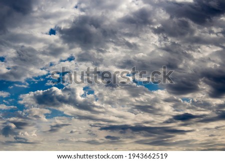 Fluffy white cumulus clouds with some darker cumulostratus and cirrus formations on a late spring afternoon are contrasted against the Australian sky creating a fascinating cloud scape.