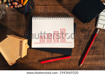 Drawing a graph of growth in a notebook on your desk at home.Wooden work table