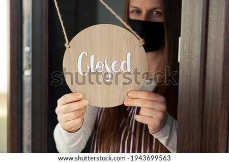 Woman holds the wooden sign with text: Closed