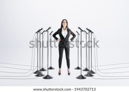 Business speaker concept with confident businesswoman and floor stand microphones around on light background