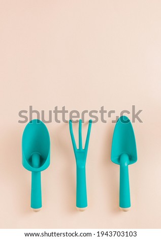 Minimal concept with teal gardening tools on beige background. Green eco arrangement.Environmental planting plants idea. Copy space.