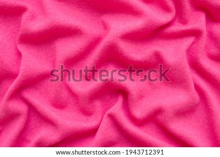 Pink wool fabric background with wavy folds. Copy space.