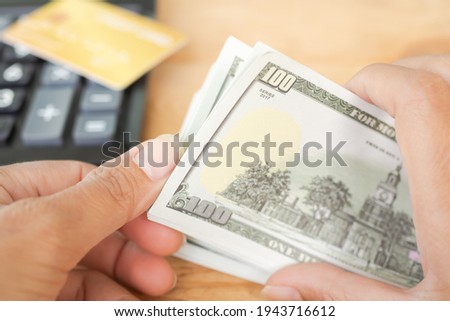 100 dollars. Close up hand woman counting money bank note with credit card and calculator blured. planing earn money investment and saving money future for 2022 new year. finance and business concept.