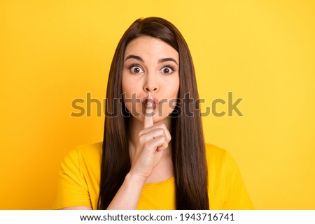 Photo of charming speechless lady finger cover lips look camera wear t-shirt isolated yellow background