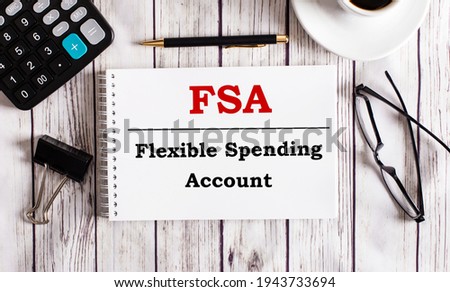 FSA Flexible Spending Account is written in a white notepad near a calculator, coffee, glasses and a pen. Business concept