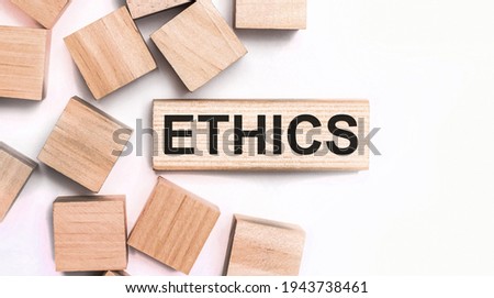 On a light background, wooden cubes and a wooden block with the text ETHICS. View from above