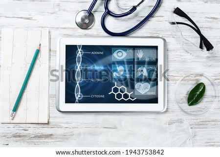 Human genetic research in modern medical laboratory. Tablet computer with DNA helix structure on screen. Stethoscope and cardiogram on wooden desk. Medical diagnostics and patient genome testing.